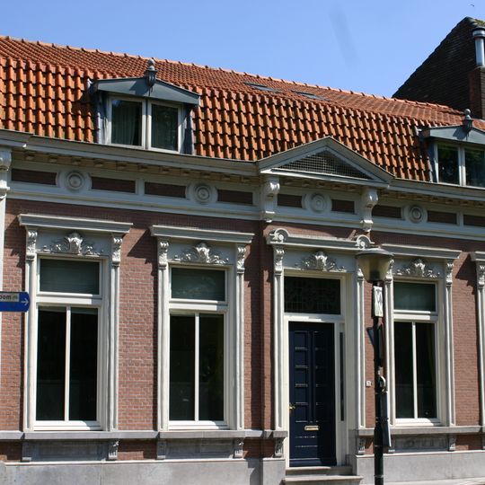 Woonhuis, gebouwd in het laatste kwart van de negentiende eeuw, in Eclectische stijl. Het hoekhuis heeft de voorgevel aan de Markt, de zijgevel grenst aan de Omgang.