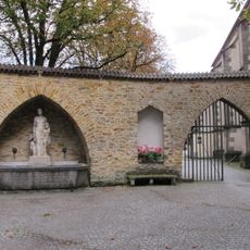 Gedächtnisbrunnen mit Becken und Statuen einer Frau mit zwei Kindern.|Zur Erinnerung an die Hundertjahrfeier der Erhebung Metzingens zur Stadt 1831-1931