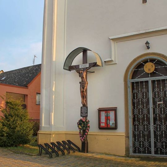 Dřevěný kříž v Třeštině u zdi kostela