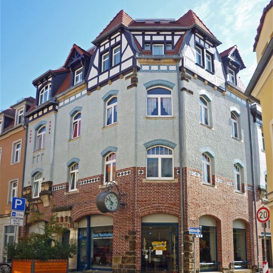 Mietshaus mit Ladenzone in Ecklage mit Anbau zur Berggasse und Werbeausleger mit Uhr Hauptstraße 21