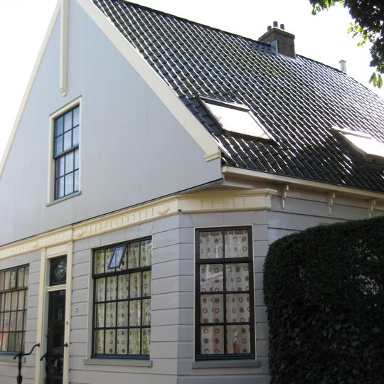 Houten dijkhuis met puntgevel, onderpui met fries in empirestijl, overhoeks geplaatst raam
