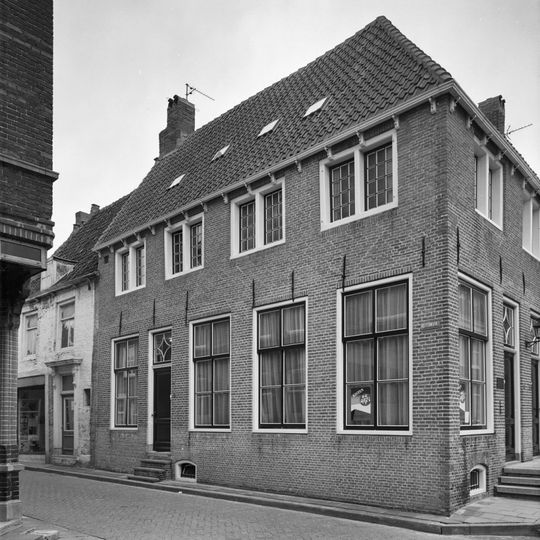 Fors onderkelderd hoekpand met zadeldaken en geverfde rechte gevels