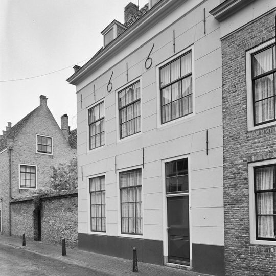 Huis met gepleisterde lijstgevel voorzien van twee dakkapellen en jaartalankers. Rozet bovenlicht