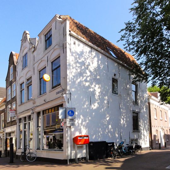 Pand met tot klokgevel gewijzigde gepleisterde trapgevel waarvan de dekplaten onder en boven bewaard zijn gebleven