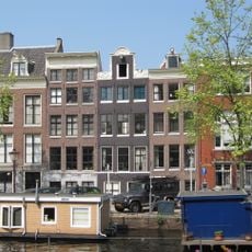 Pand met gevel oorspronkelijk halsgevel, verhoogd met een verdieping onder lijst met triglyfen