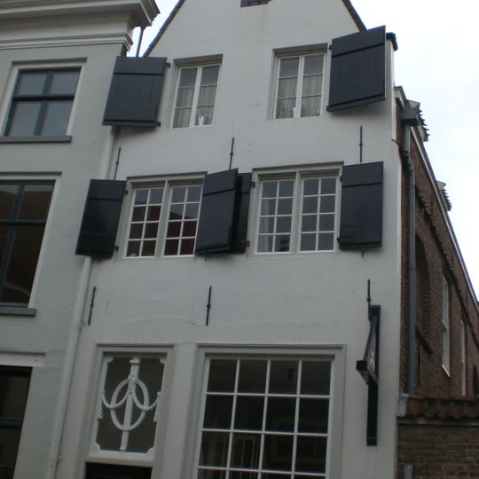 Huis met gepleisterde tuitgevel, afgedekt door eensteens rollaag