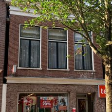 Pand met vernieuwde voorgevel met rechte kroonlijst onder zadeldak met voorschild en topschoorsteen met bord