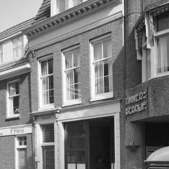 Pand met geblokte rechte kroonlijst en ingangsomlijsting met gesmede ramskoppen