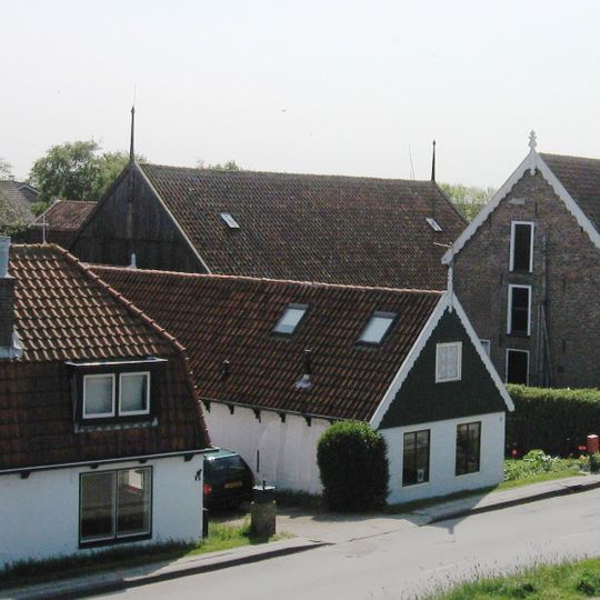 Pand opgetrokken zonder verdieping onder langgerekt pannen zadeldak tussen puntgevels met houten top