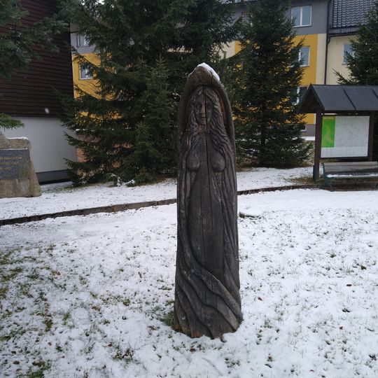 Dřevěná socha mužíka v parčíku