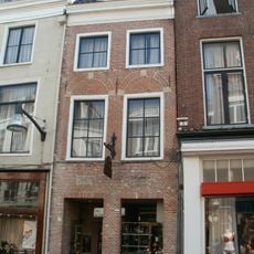 Smal pand met twee verdiepingen en rechte kroonlijst waarboven dakkapel