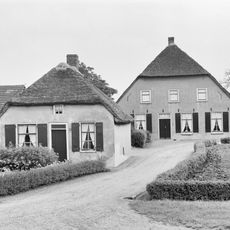 Grote boerderij met gepleisterd woongedeelte, waarin vensters met luiken en zes- en negenruitsschuiframen