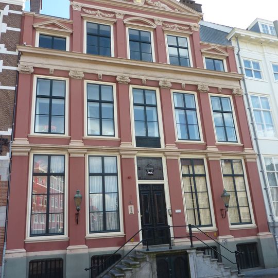 Pand met gevel op hardstenen plint, hardstenen stoep-toepassing van drie pilasterorden boven elkaar - middenpartij met drie traveeën gedekt door een driehoekig fronton met wapenschilden