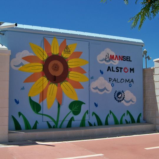 Mural representando un girasol en la parte frontal del edificio y un panel solar en uno de sus laterales.