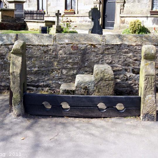 Stocks circa 5 metres south of lychgate to Church of St. Anne