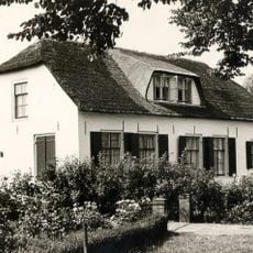 Boerderij bestaande uit een gepleisterd dwarshuis en een bedrijfsgedeelte, onder een met riet gedekt wolfdak