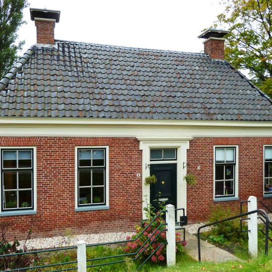 Pand met omlijste ingang onder schilddak met hoekschoorstenen met borden