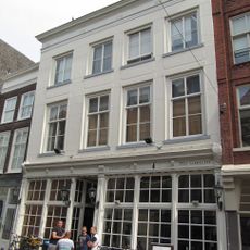 Pand achter brede gepleisterde lijstgevel ter breedte van vier vensters