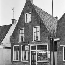 Pand onder zadeldak tussen topgevels met top met lijsten en zes- en vierruitsvensters