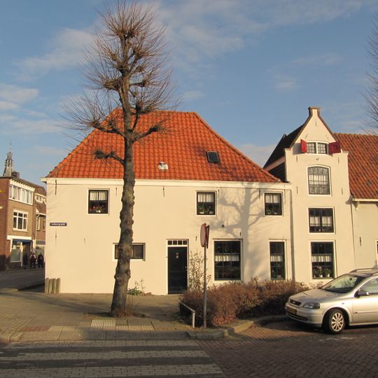 Drie ongenummerde panden, gepleisterde rechte gootlijst, in midden een topgevel