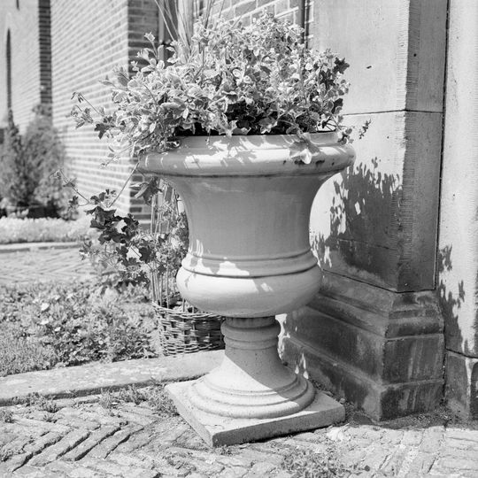 Twickel: twee gietijzeren, grijs geschilderde tuinvazen in kelkvorm voor ingangspartij bouwhuizen