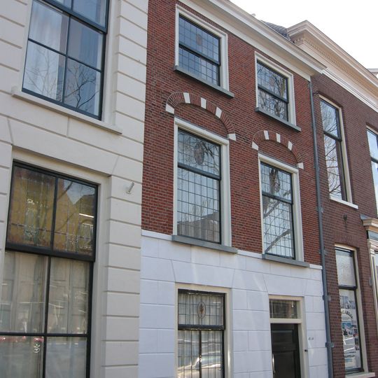 Pand onder schilddak en met afgeknotte en door rechte lijst afgedekte gevel, waarin geblokte ontlastingsbogen