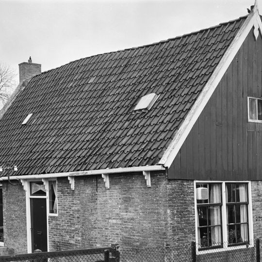 Eenvoudig pand onder zadeldak tussen topgevels, waarvan een met houten voorschot