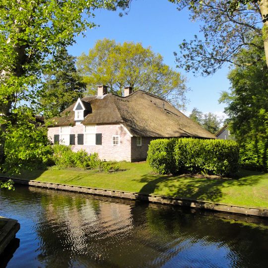 Dwarswoning onder met pannen gedekt schilddak met bedrijfdeel onder rieten schilddak