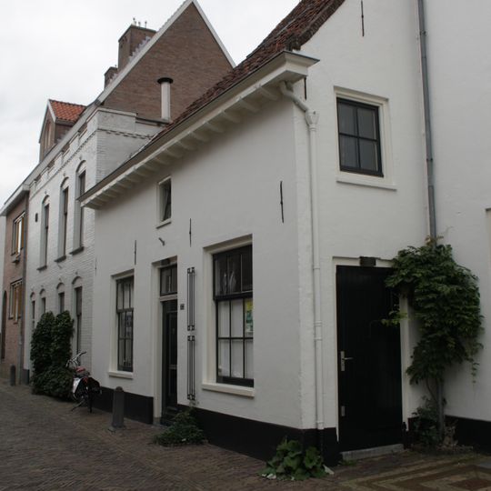 Laag eenvoudig gepleisterd huis, uitspringend naast nr 35b