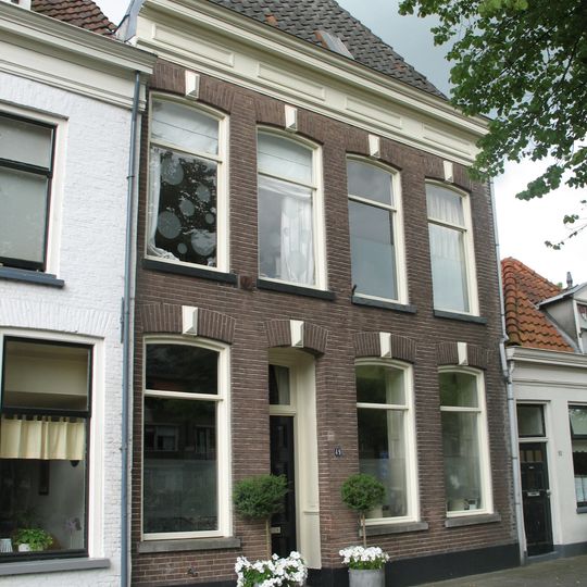 Pand met kroonlijst met panelen en getoogde vensters onder hoog schilddak