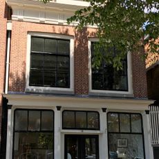 Pand met hoge verdieping en kroonlijst met gesneden consoles onder schilddak met topschoorsteen