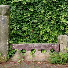 Stocks Approximately 5 Metres North Of East Gate To Church