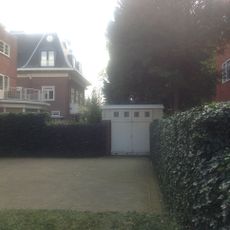 Garage in rode baksteen op rechthoekig grondplan en gedekt door een plat dak