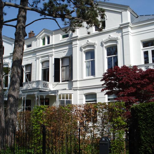 Vrijstaand blok van drie geschakelde villa's met diepe voortuinen achter een gietijzeren hek in eclectische trant