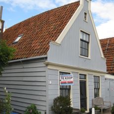 Houten huis, gepotdekselde zijwanden en puntvormig voorschot. Goede pui en puilijst