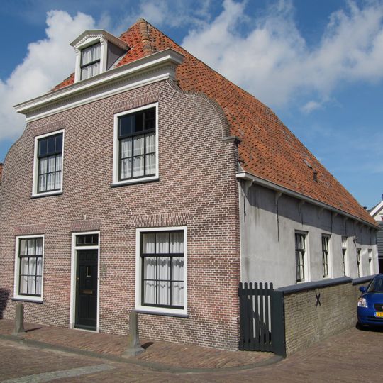 Pand onder hoog, pannen zadeldak, dat aan de voorzijde is afgewolfd