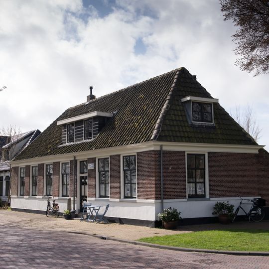 Pand van baksteen. Vensterbogen met natuursteenblokken en maskersluitstenen. Twee dakkapellen. Vermoedelijk deel uitmakend van de oorspronkelijke dienstgebouwen van het kasteel