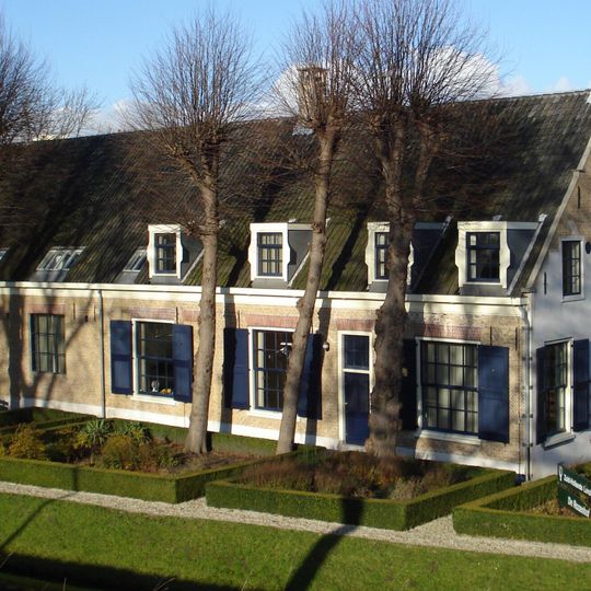 Boerderij, bestaande uit een parallel aan de dijk gebouwd woonhuis, waarnaast de stal, beide onder een hoog zadeldak. Achtervleugel onder zadeldak met puntgevel.