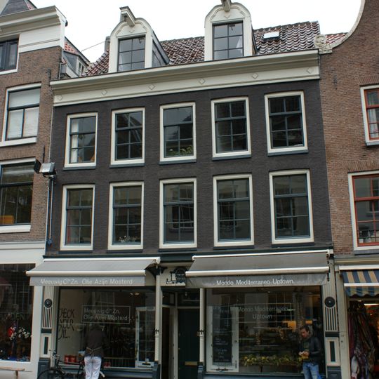 Etagewoningencomplex met gezamenlijke gevel onder rechte lijst en dwars dak waarin twee dakkapellen met snijwerk