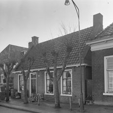 Eenvoudig pand met zesruitsvensters onder dwars zadeldak tussen topgevels