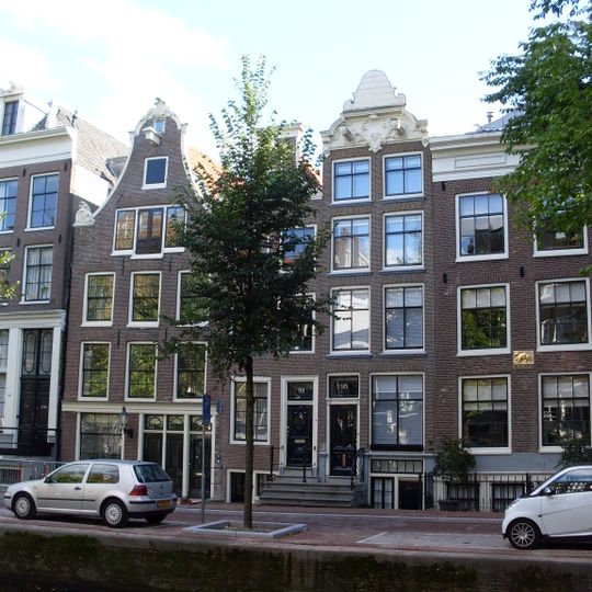 Pand met zeer smalle gevel onder rijk gesneden getoogde lijst waarin twee hijsbalken met maskers aan de uiteinden