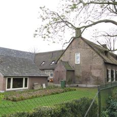 Boerenwoning onder rieten zadeldak en voorzien van ramen met kleine roedenverdeling