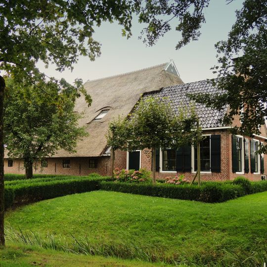 Kop-rompboerderij met zesruitsvensters, omgaande houten goot en schuur onder rieten dak