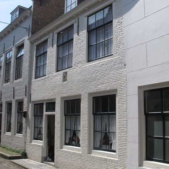 Huis met geverfde rechte gevel met gootlijst op klossen