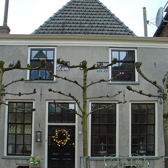 Huis met eenvoudige gepleisterde gevel met rechte kroonlijst, twee gevelstenen met eenhoorns in rolwerk-cartouches, steen met engelenkopje en sierankers