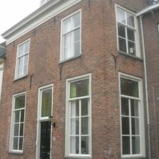 Woonhuis met rechte kroonlijst. 19e-eeuws voorkomen. In de vooruitspringende hoek een spiongat