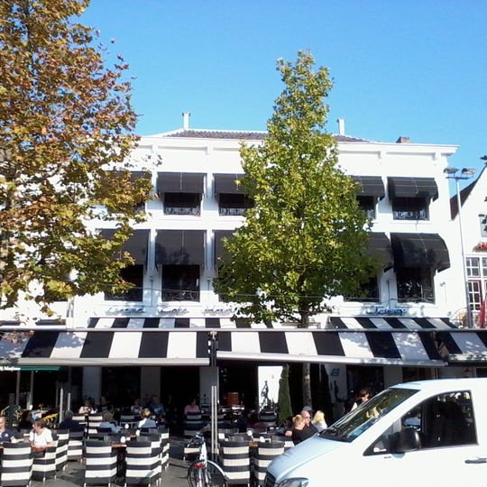 Dubbelpand met gemeenschappelijke, wit gepleisterde lijstgevel van zes traveeën breed en langs de voorgevel een stoep met smeedijzeren stoephekken