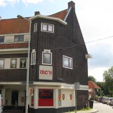 Blok met winkels met brede luifel en daarboven woningen, bouwstijl Amsterdamse School, onderdeel van het centrale achthoekige plein van Tuindorp Nieuwendam