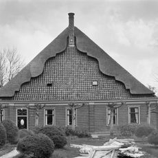 Stolphoeve. Het voorgevelvlak wordt geleed door geblokte lisenen en horizontaal afgesloten door een kroonlijst. Gesneden voordeur en bovenlicht