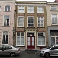 Huis met witgepleisterde lijstgevel en kroonlijst op voluutvormige consoles